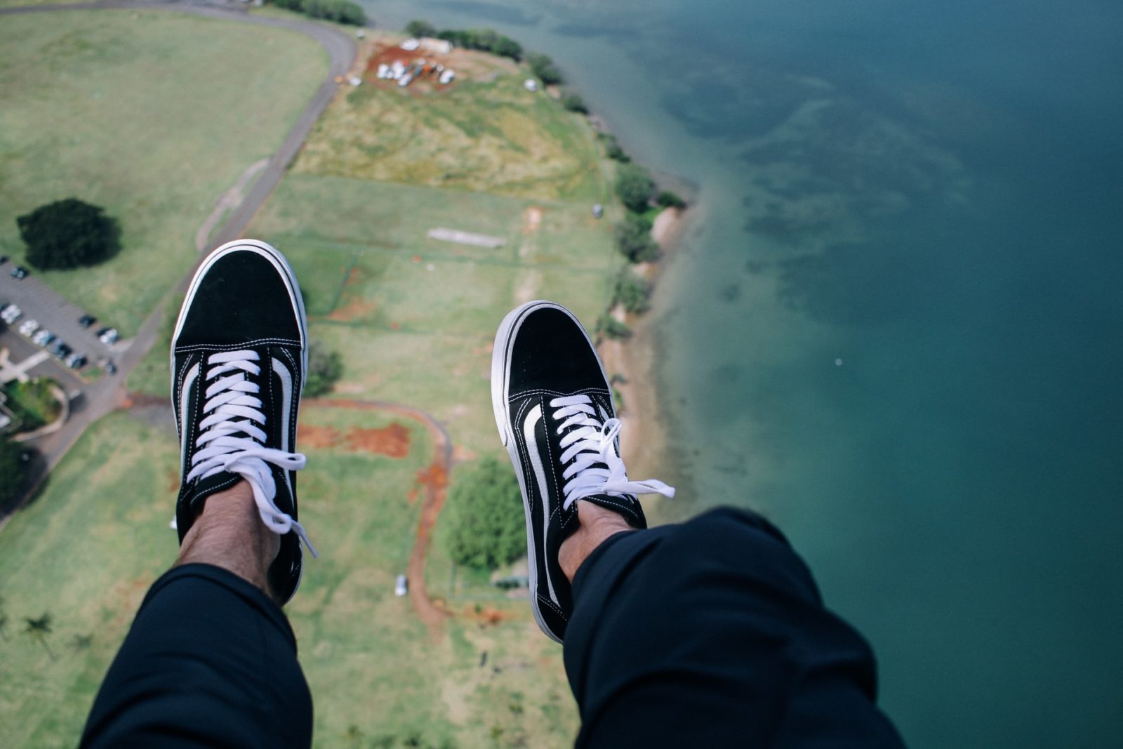 a person's legs and feet on a cliff by the water