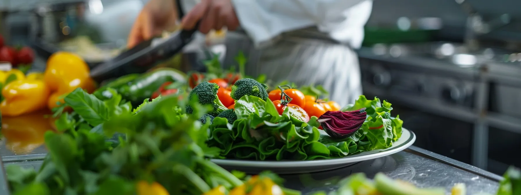 green leaves and colorful vegetables being carefully arranged on a plate in a professional kitchen.