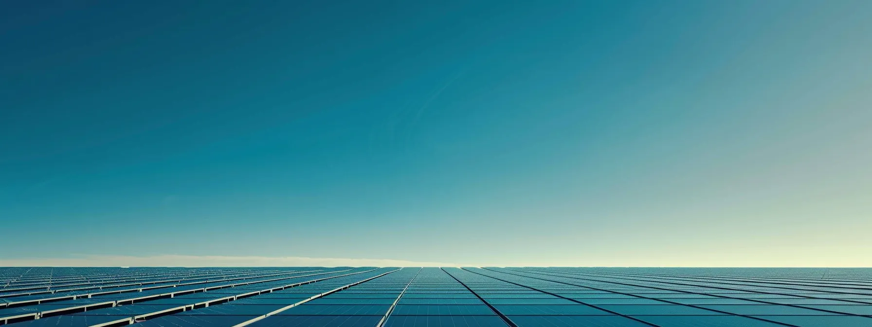 a field of solar panels stretching towards the horizon under a clear blue sky.