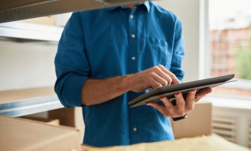 Cropped shot of young man using digital tablet in warehouse while doing inventory and managing small business, copy space